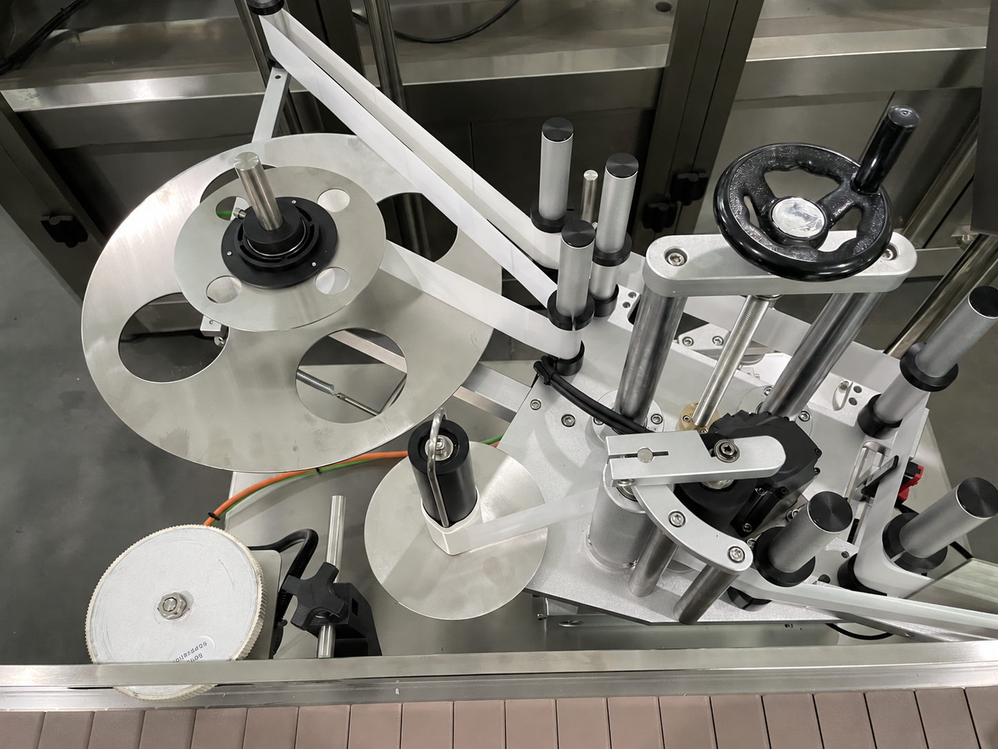 Real bottle labeling mechanism with bottle guides and label application components
